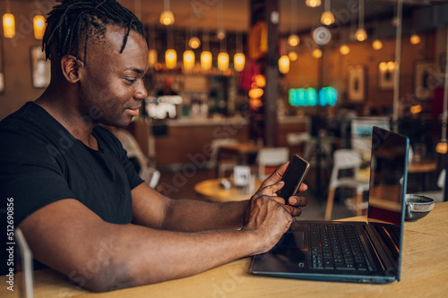 African american man using laptop while drinking coffee in a cafe