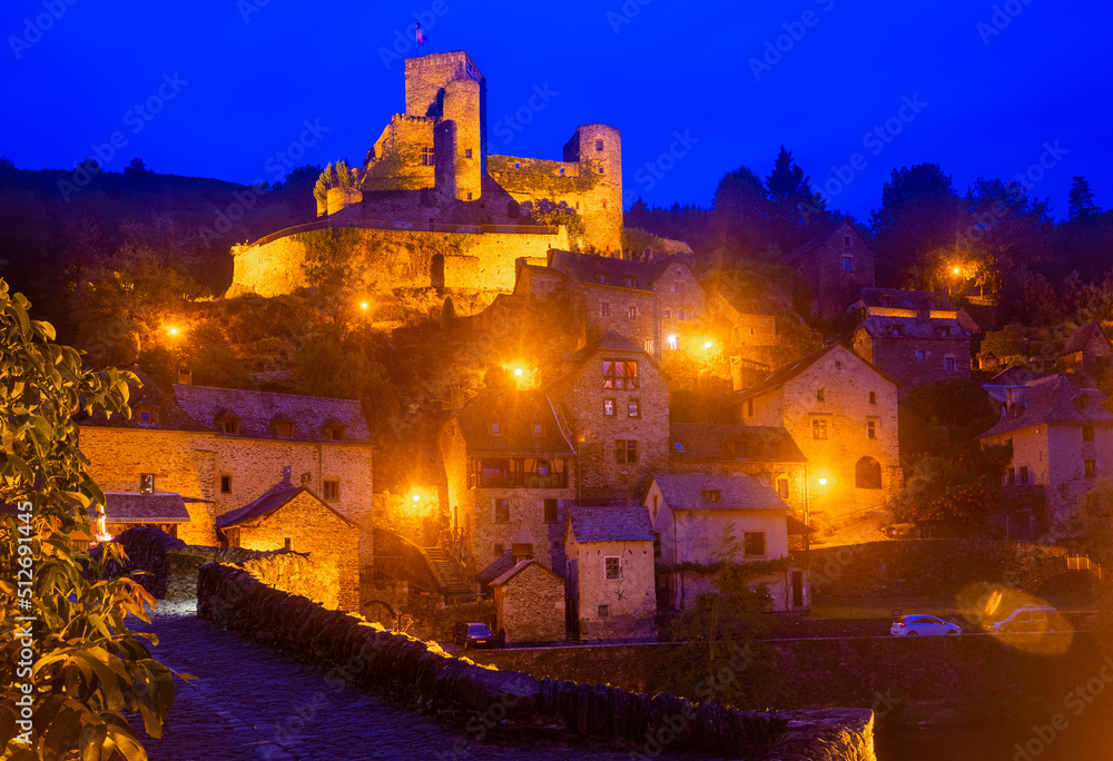 Night view of illuminated fortified Chateau de Belcastel rising above medieval Belcastel village in summer, Aveyron, France