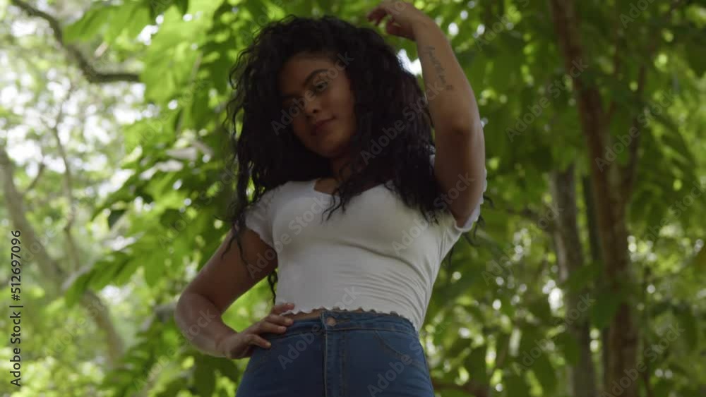 Low angle shot of a curly hair model playing in her hair at the park Low angle shot of a curly hair model playing in her hair at the park