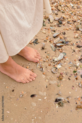 feet on the beach between the shells
