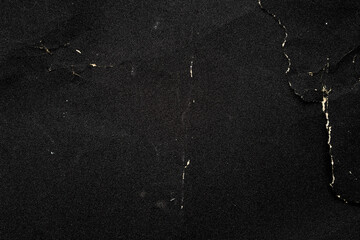 Crumpled black paper with a detailed texture. Close up the paper with white cracks. Rough paper texture for background.