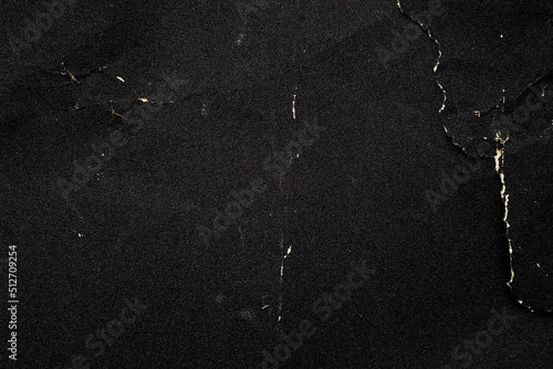 Crumpled black paper with a detailed texture. Close up the paper with white cracks. Rough paper texture for background.
