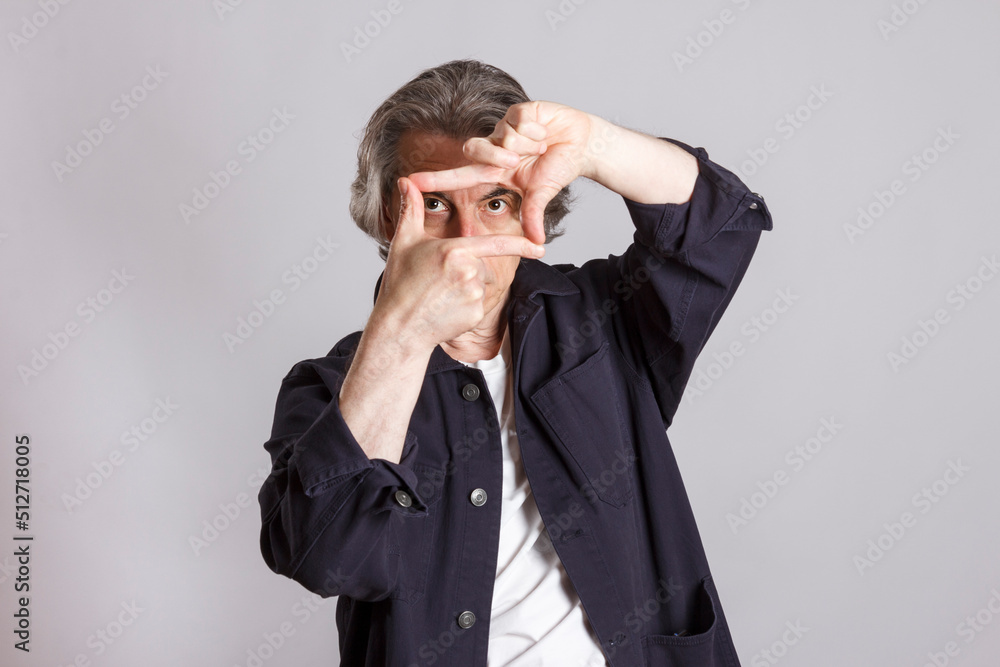 The man looks through the frame from the fingers of his hands. The man looks through the frame from the fingers of his hands.