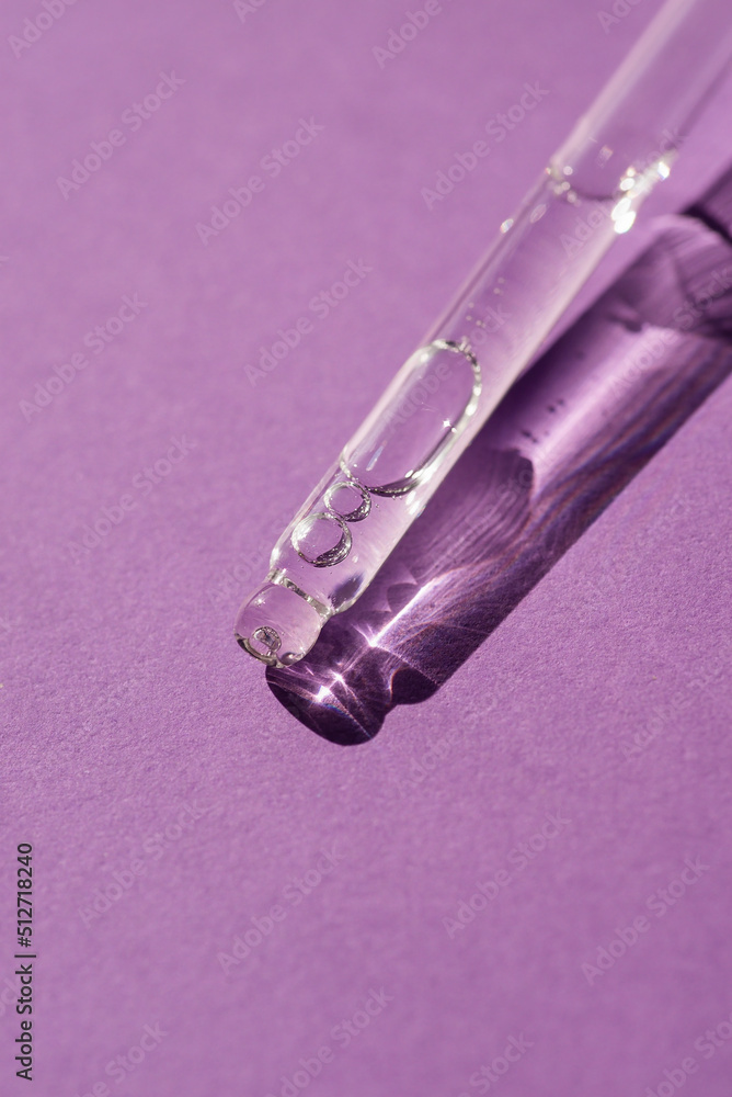 Naklejka premium Pipette with serum or cosmetic liquid close-up on a purple background in soft focus. Beautiful shadow in the sunlight. Skincare products , natural cosmetic. Beauty concept for face and body care