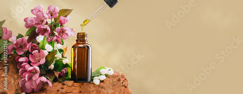 Quadro em tela Natural medicine or aroma oil or beauty essence concept vial with dropper on stone podium stand with pink flowers and golden brown background