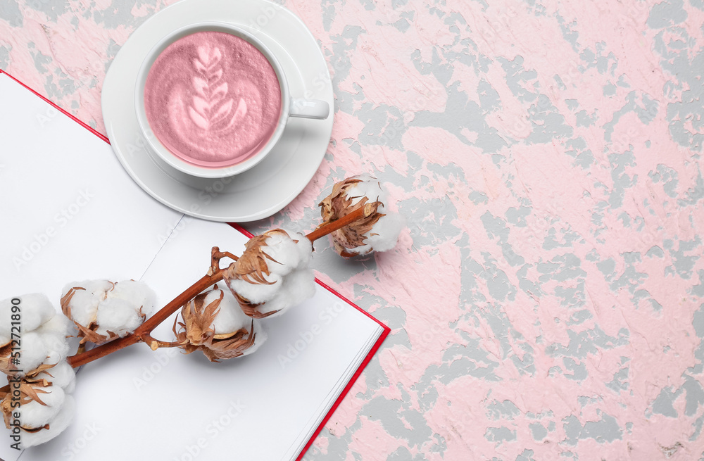 Cup of pink matcha tea with book and cotton flowers on color background with space for text Cup of pink matcha tea with book and cotton flowers on color background with space for text