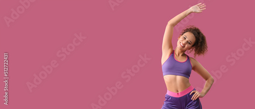 Sporty young African-American woman training on pink background with space for text