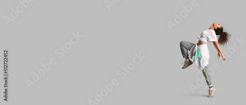 Female African-American hip-hop dancer on grey background with space for text