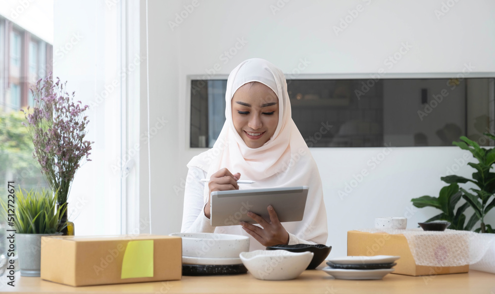 Attractive muslim female entrepreneur, e-commerce business owner packing preparing a shipping box in her office. Attractive muslim female entrepreneur, e-commerce business owner packing preparing a shipping box in her office.