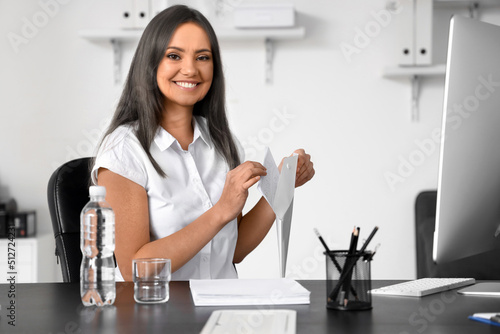 Smiling senior businesswoman working with documents at table in office. Process of aging
