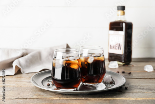 Glasses of cold brew coffee on wooden table against white background