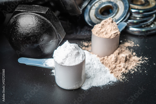 Scoop of protein powder and dumbbell background,Sports supplement,Fitness or healthy lifestyle concept. selective focus photo
