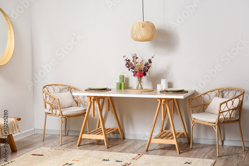 Stylish dining table and armchairs near light wall