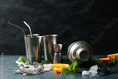 Set of cocktail utensils and ingredients on table against dark background