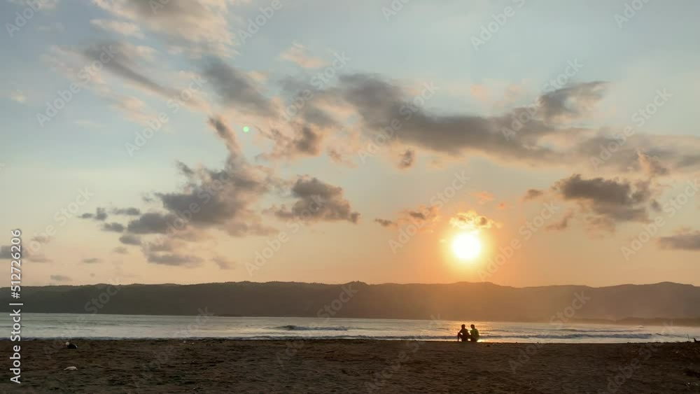 The landscape of the beach during sunset with the silhouette two friends enjoying the view The landscape of the beach during sunset with the silhouette two friends enjoying the view
