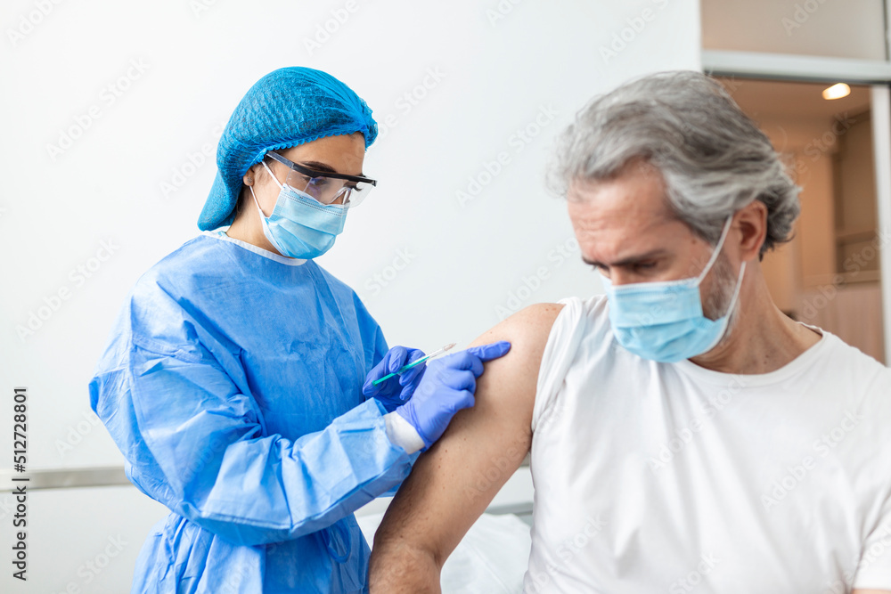 Vaccination, immunization, disease prevention concept. Man in medical face mask getting Covid-19 or flu vaccine at the hospital. Professional nurse or doctor giving antiviral injection to patient Vaccination, immunization, disease prevention concept. Man in medical face mask getting Covid-19 or flu vaccine at the hospital. Professional nurse or doctor giving antiviral injection to patient