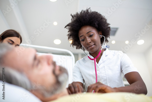 Senior patient on bed talking to African American female doctor in hospital room, Health care and insurance concept. Doctor comforting elderly patient in hospital bed or counsel diagnosis health. photo