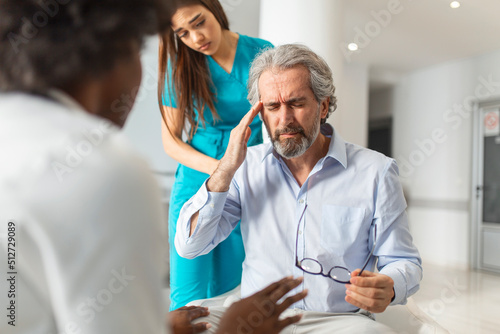 Female doctor reassuring supporting senior adult patient in hospital. Kind caring young woman nurse or caregiver helping older retired man talking, giving comfort, expressing care concept.