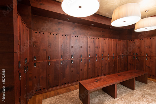 Interior of a locker room. Clean empty dressing room with big lockers with wooden door and wooden bench