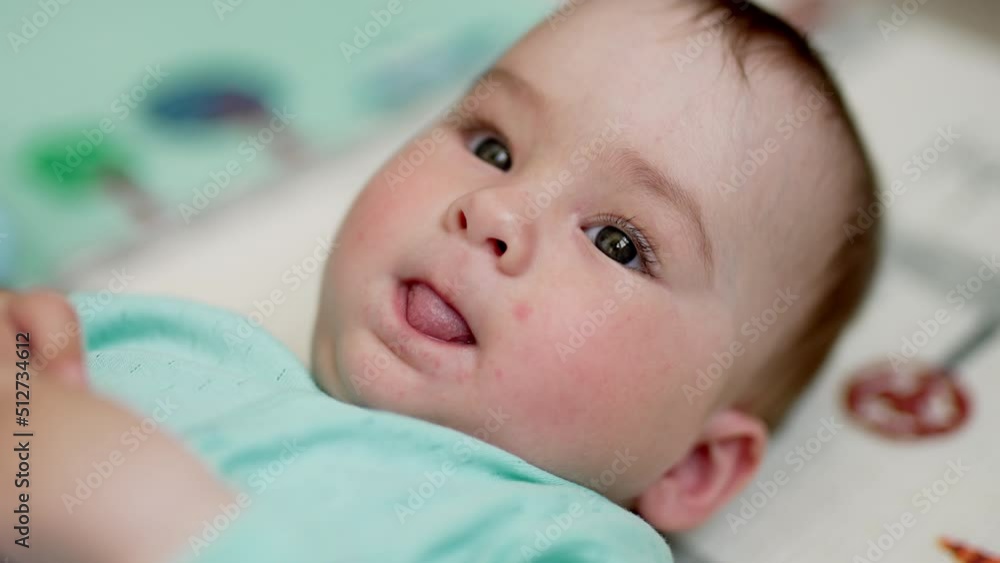 Lovely calm baby lying in his crib with eyes open. Beautiful child showing tongue to the camera. Close up. Lovely calm baby lying in his crib with eyes open. Beautiful child showing tongue to the camera. Close up.