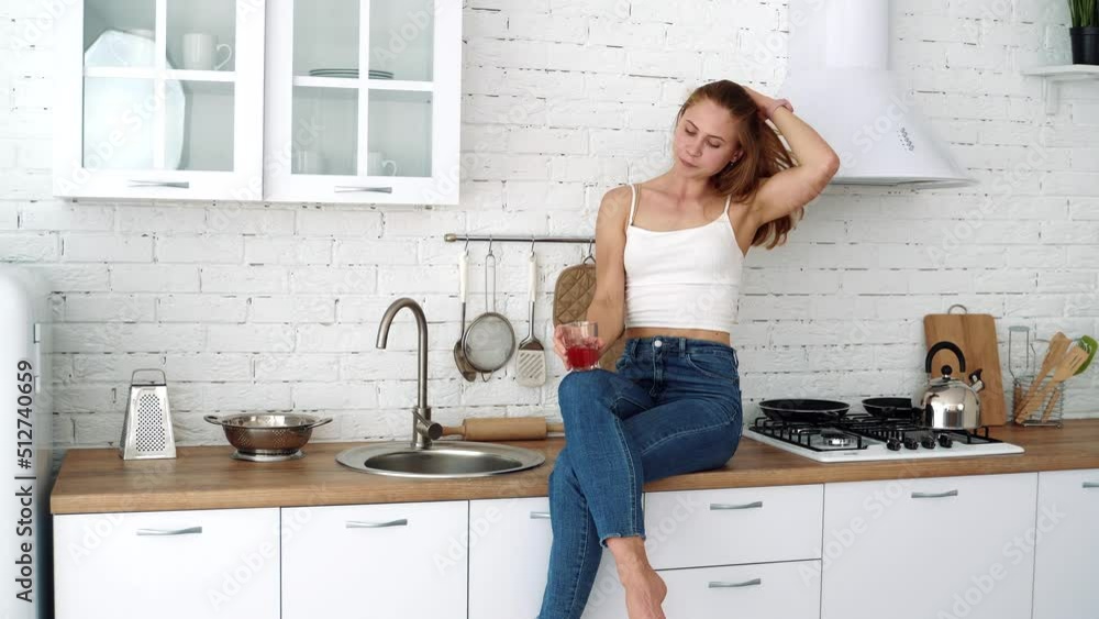 Young woman drinks juice from a glass in the kitchen. Healthy food, diet. Young woman drinks juice from a glass in the kitchen. Healthy food, diet.