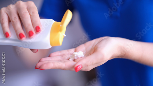 Woman pouring moisturizing body lotion from bottle on hand closeup