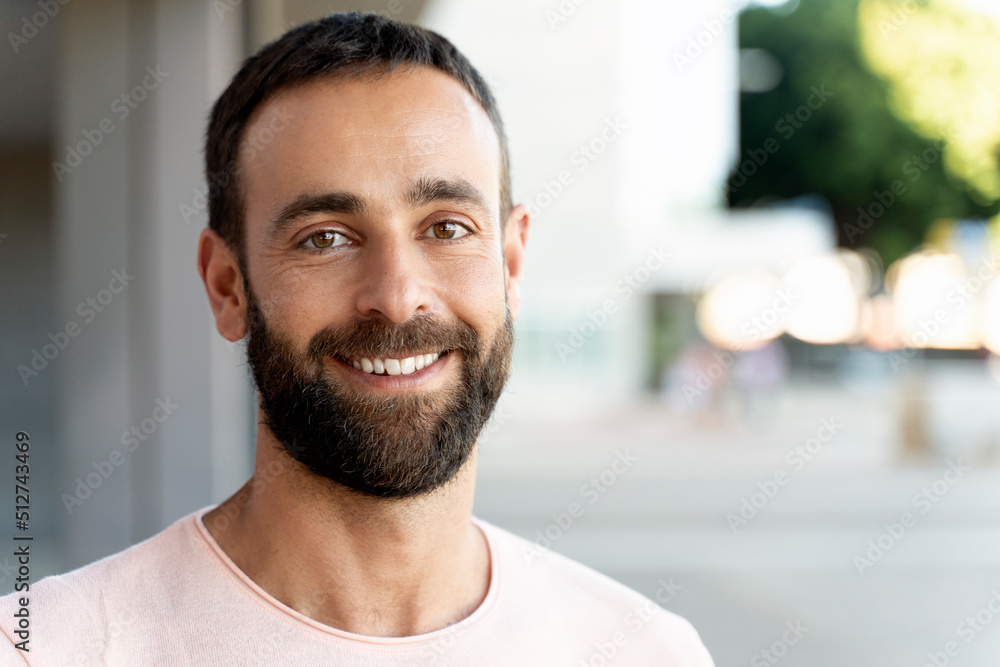 Portrait of smiling handsome man looking at camera on the street, copy space. Happy confident client after beard cut in barbershop  
