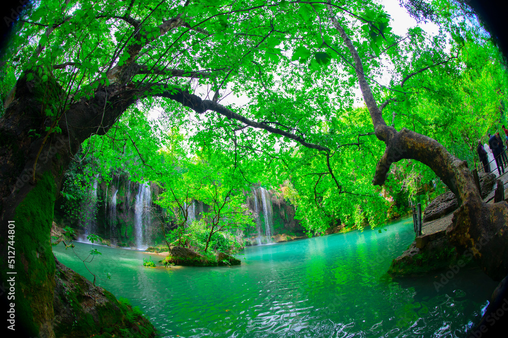 Obraz premium A photo looking through the threes to the tranquil waterfall at Kursunlu in Antalya, Turkey.