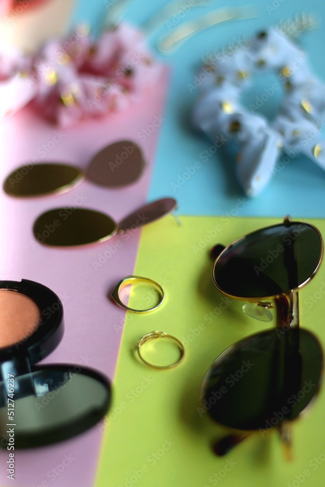 Various accessories, make up products and jewelry on various colorful pastel backgrounds. Selective focus. Various accessories, make up products and jewelry on various colorful pastel backgrounds. Selective focus.