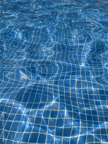 Blue rippled water in the swimming pool on a sunny day with sun reflection