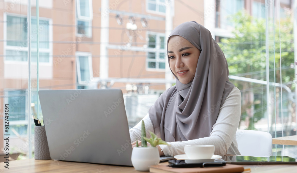 Asian Muslim business woman in hijab headscarf working with computer laptop in the modern office. business people, diversity and office concept Asian Muslim business woman in hijab headscarf working with computer laptop in the modern office. business people, diversity and office concept