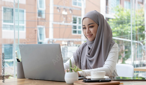 Fotografie Asian Muslim business woman in hijab headscarf working with computer laptop in the modern office