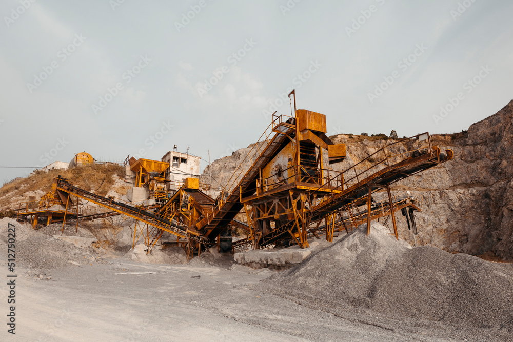 Quarry machines and piles of gravel over blue sky. Stone crushing and screening plant Quarry machines and piles of gravel over blue sky. Stone crushing and screening plant