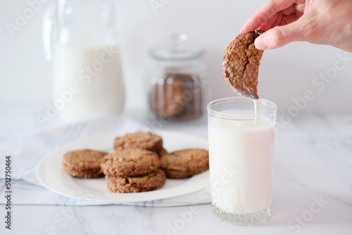 Canvas Print Woman's hand dipping homemade cookies into a glass of milk