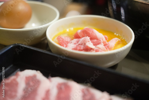 Slice beef dip in raw egg for cooking sukiyaki