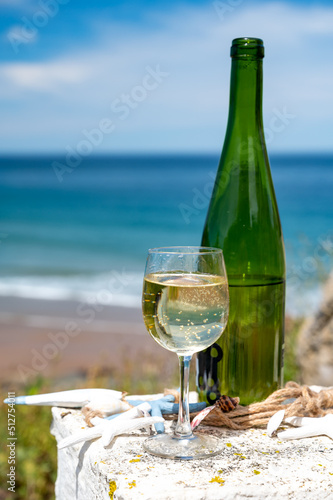 Txakoli or chacolí slightly sparkling very dry white wine produced in the Spanish Basque Country, served outdoor with view on Bay of Biscay, Atlantic Ocean. photo