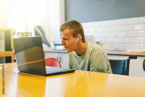 Handsome young invalid disabled man talking on mobile phone in kittchen. Person with disabilities. Video chat or call. Portrait of man handicapped with disabilities. Optimistic smiling disabled man. photo