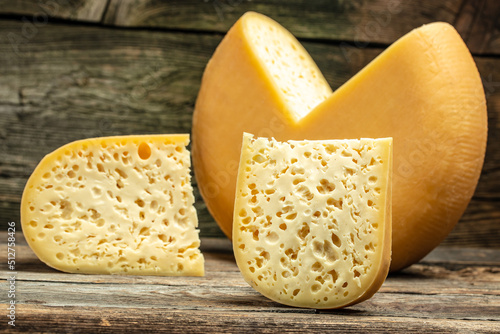 Cheese wheel with a piece of cheese maasdam with big holes. farmer market. banner, menu, recipe place for text photo