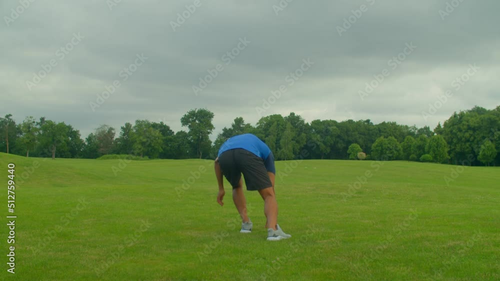 Active motivated fit African male football player in sport jersey training agility drills, improving speed and quickness, practicing run to cone and cut exercises on green field outdoors. Active motivated fit African male football player in sport jersey training agility drills, improving speed and quickness, practicing run to cone and cut exercises on green field outdoors.