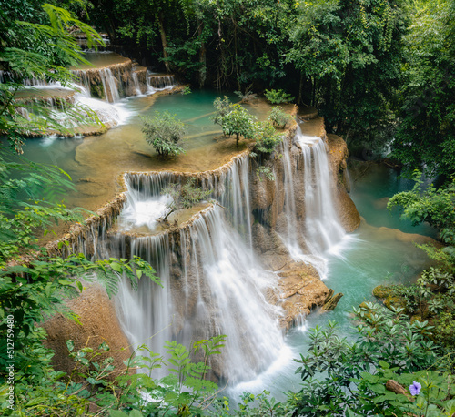 Beautiful waterfall in the tropical jungle at Kanchanaburi, Thailand. Emerald green waters in the forest.