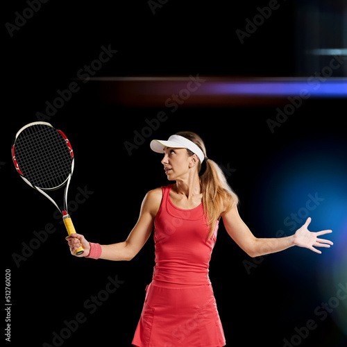 Young beautiful girl playing tennis on dark studio background © Denys Kurbatov