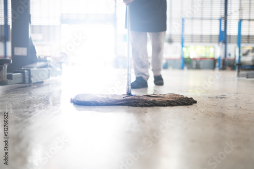 mechanic in auto repair center Cleaning using a mop Squeeze water from the epoxy floor. in the car repair service center