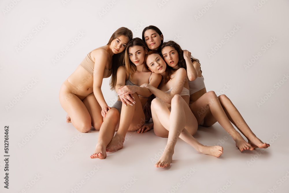 Portrait of five beautiful young women with natural makeup posing in underwear isolated over grey studio background