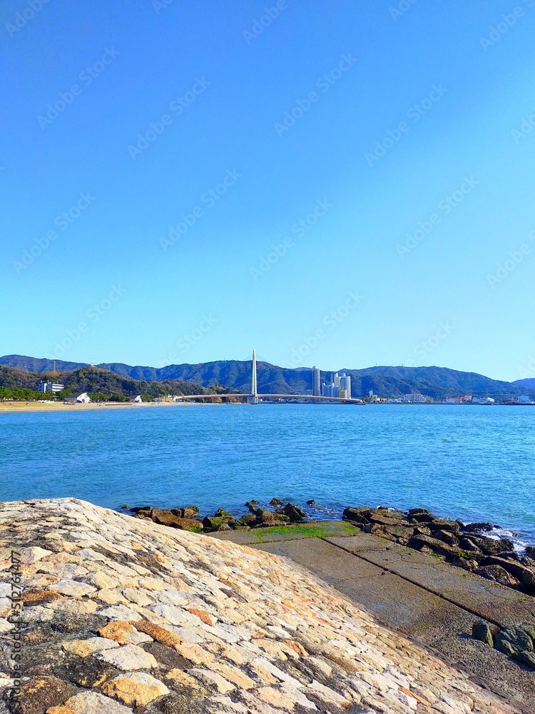 和歌山県の観光地、日本遺産和歌の浦にある片男波海水浴場の防波堤と青空と海の晴れた夏の日の爽快な風景（コピースペースあり）