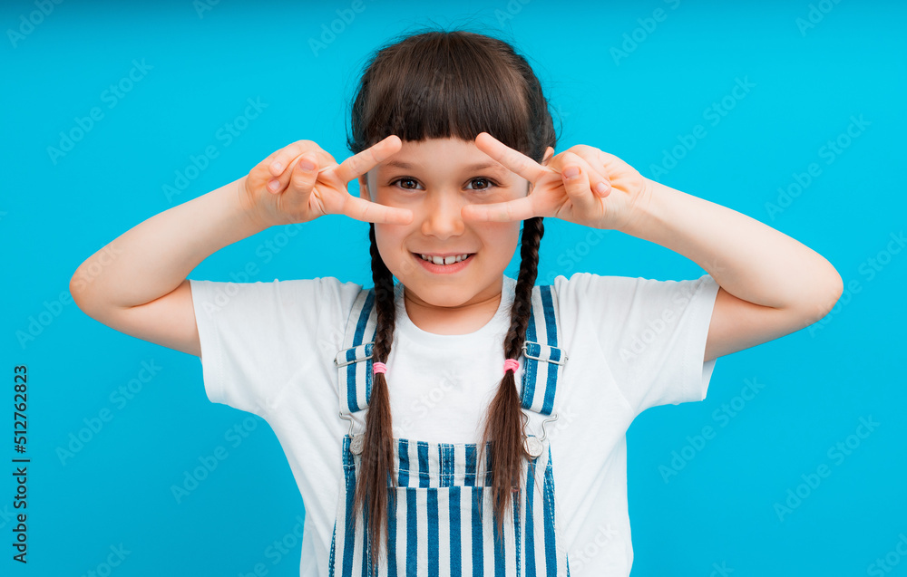 Portrait of a brunette baby girl with pigtails, make a V-shaped sign on the eyes Portrait of a brunette baby girl with pigtails, make a V-shaped sign on the eyes