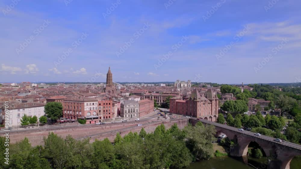 drone aerial view of Montauban in the south of france with a bridge, red stone buildings, greenery and beautiful churches visible. Cars drive freely in front of the town and on the bridge drone aerial view of Montauban in the south of france with a bridge, red stone buildings, greenery and beautiful churches visible. Cars drive freely in front of the town and on the bridge
