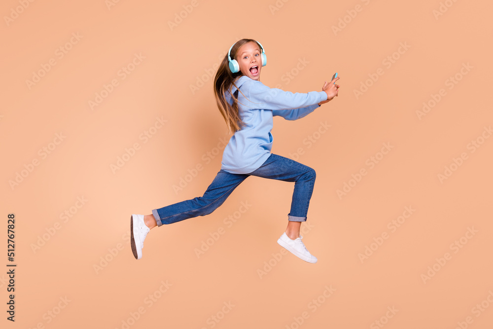 Full length profile portrait of carefree excited girl jump rush fast use hold telephone isolated on beige color background