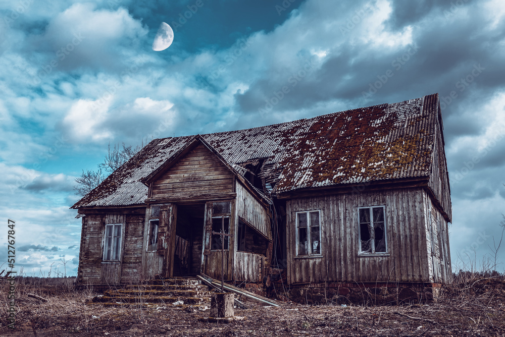 Obraz premium Old neglected wooden house,dramatic clouds at night. Abandoned Haunted Horror House.Darkness with a moon.Toned.