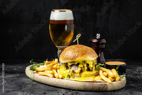 Tasty big burger and beer glass on wood tray. American food concept. fast food meal. banner  menu  recipe  place for text