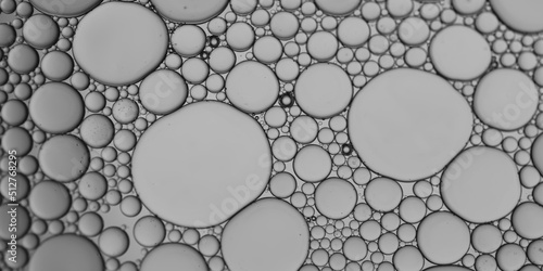 Oil and water bubbles of different sizes air bubble an attractive pattern with grey-silver gradient lighting effect to create an art image background.